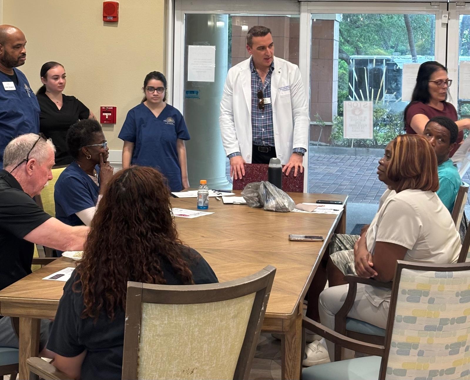 Razvan Gheorghe leading dementia education session with ALF staff seated around table in Jensen Beach